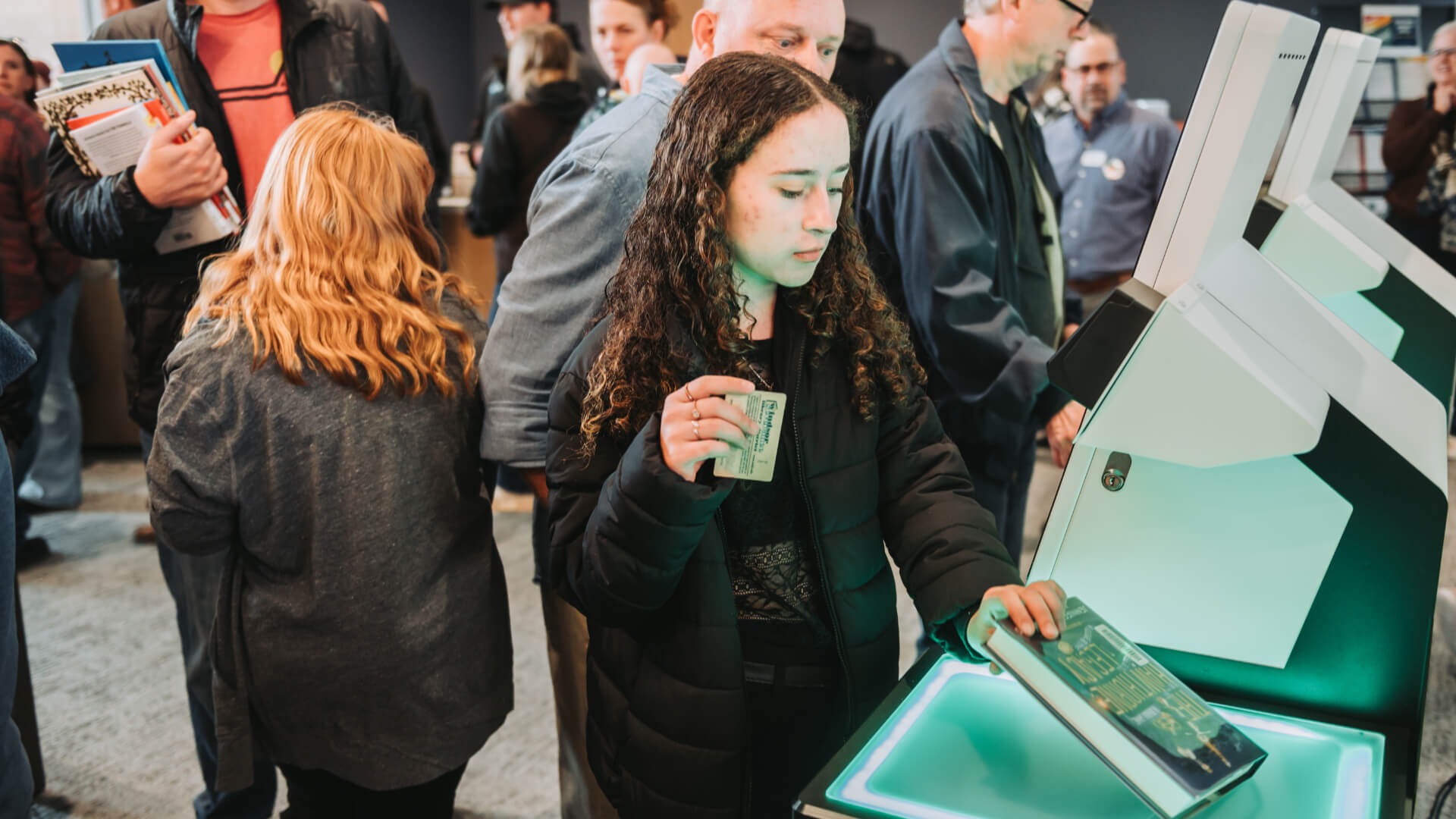 Woman checking out a library book at a self-check machine.