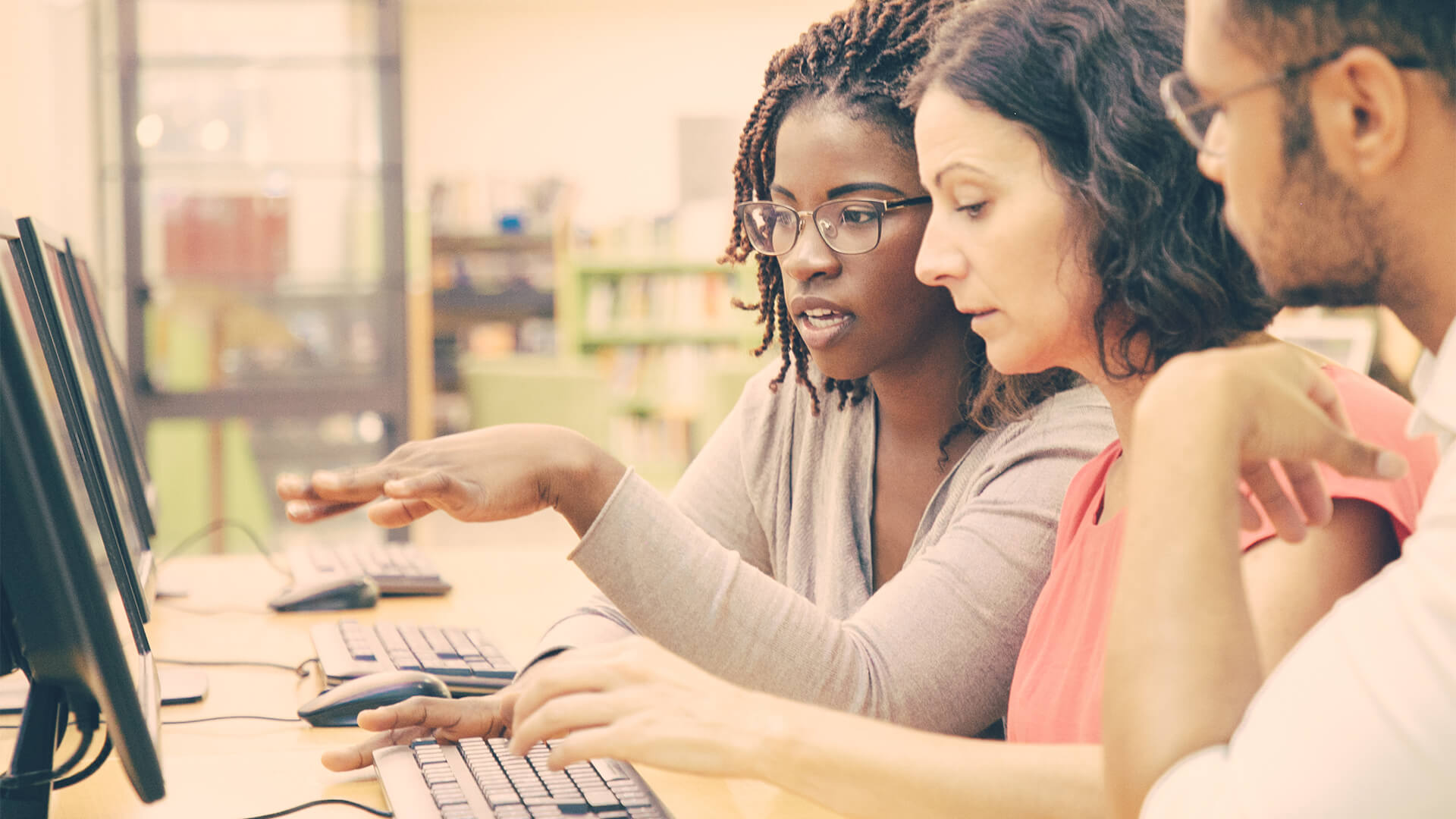 Woman helping man and woman on computers
